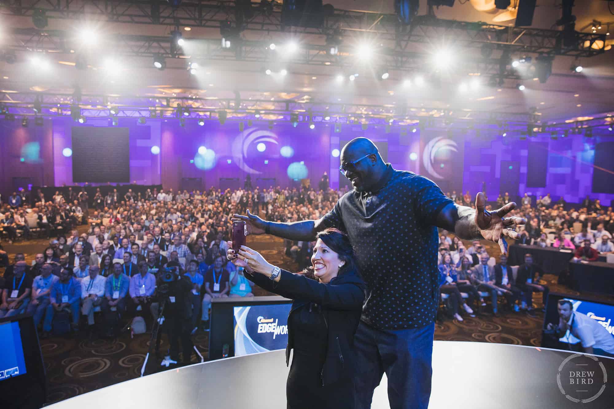 Photo of two people taking a selfie on a stage in front of an audience at a corporate event. Photo by San Francisco based photographer Drew Bird.