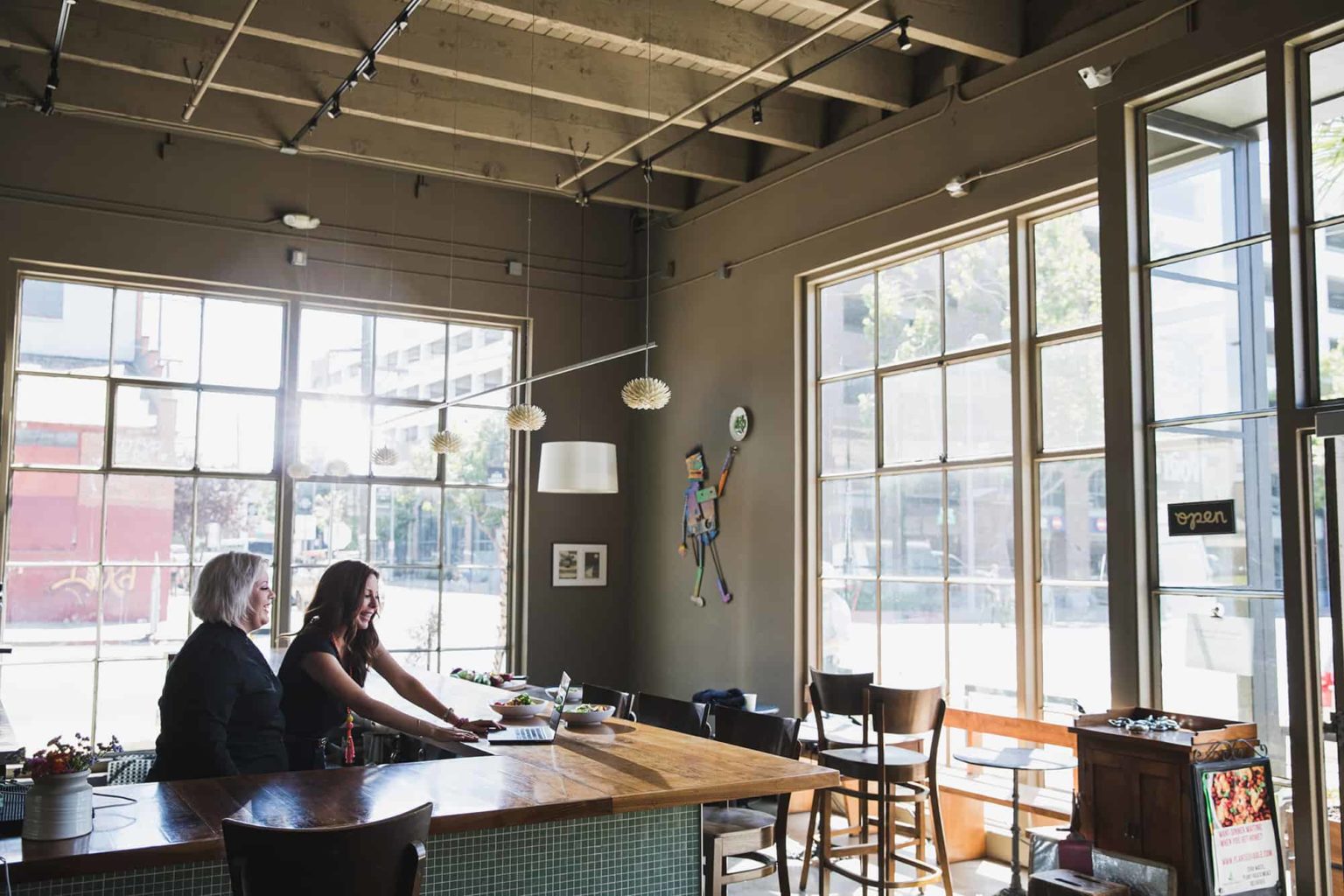 Two women working on a laptop computers at a bar. Movie set unit still photographer in San Francisco Drew Bird.