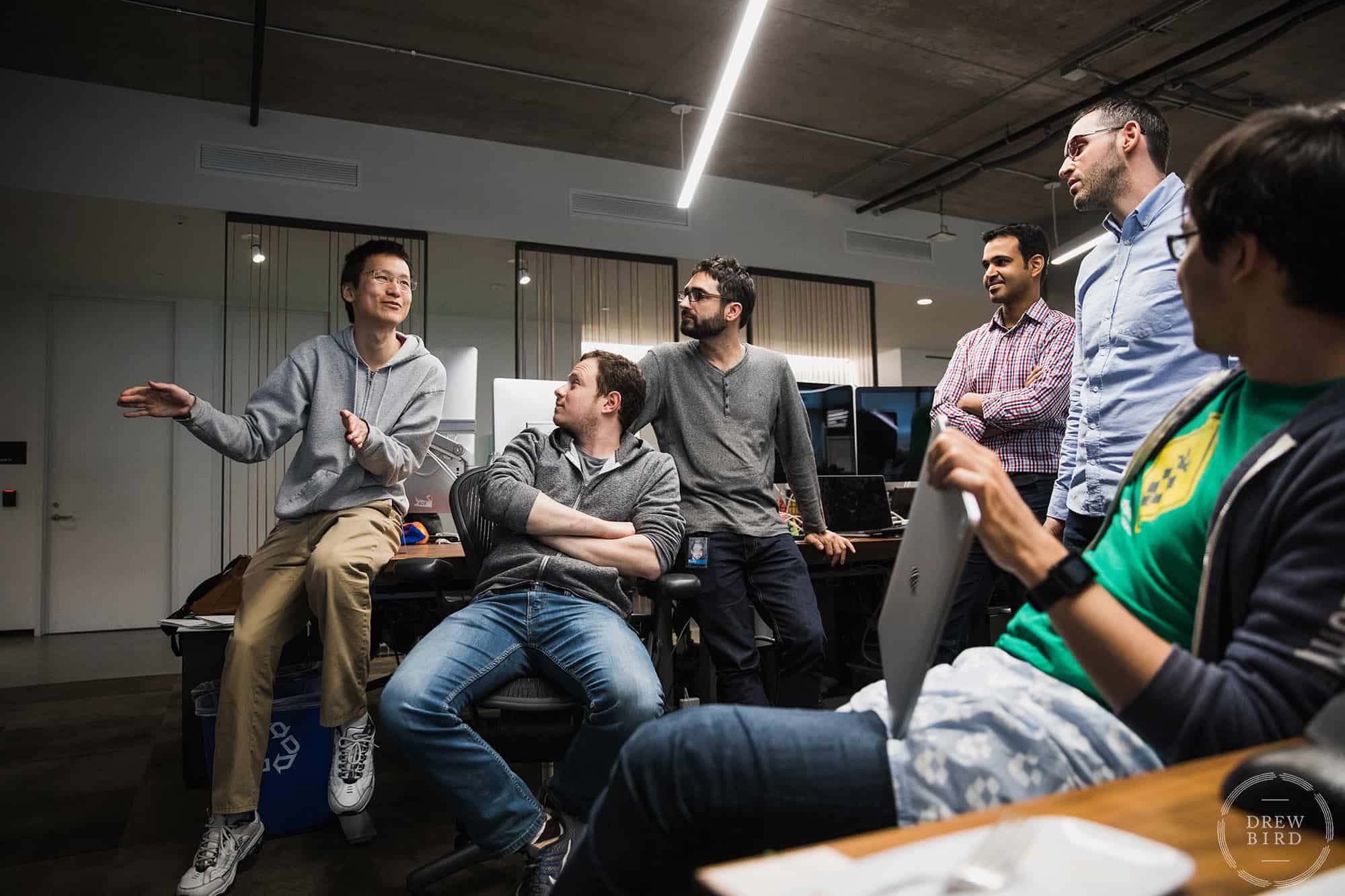 Corporate branding photography in San Francisco shows a group of casually dressed men brainstorming about a project.