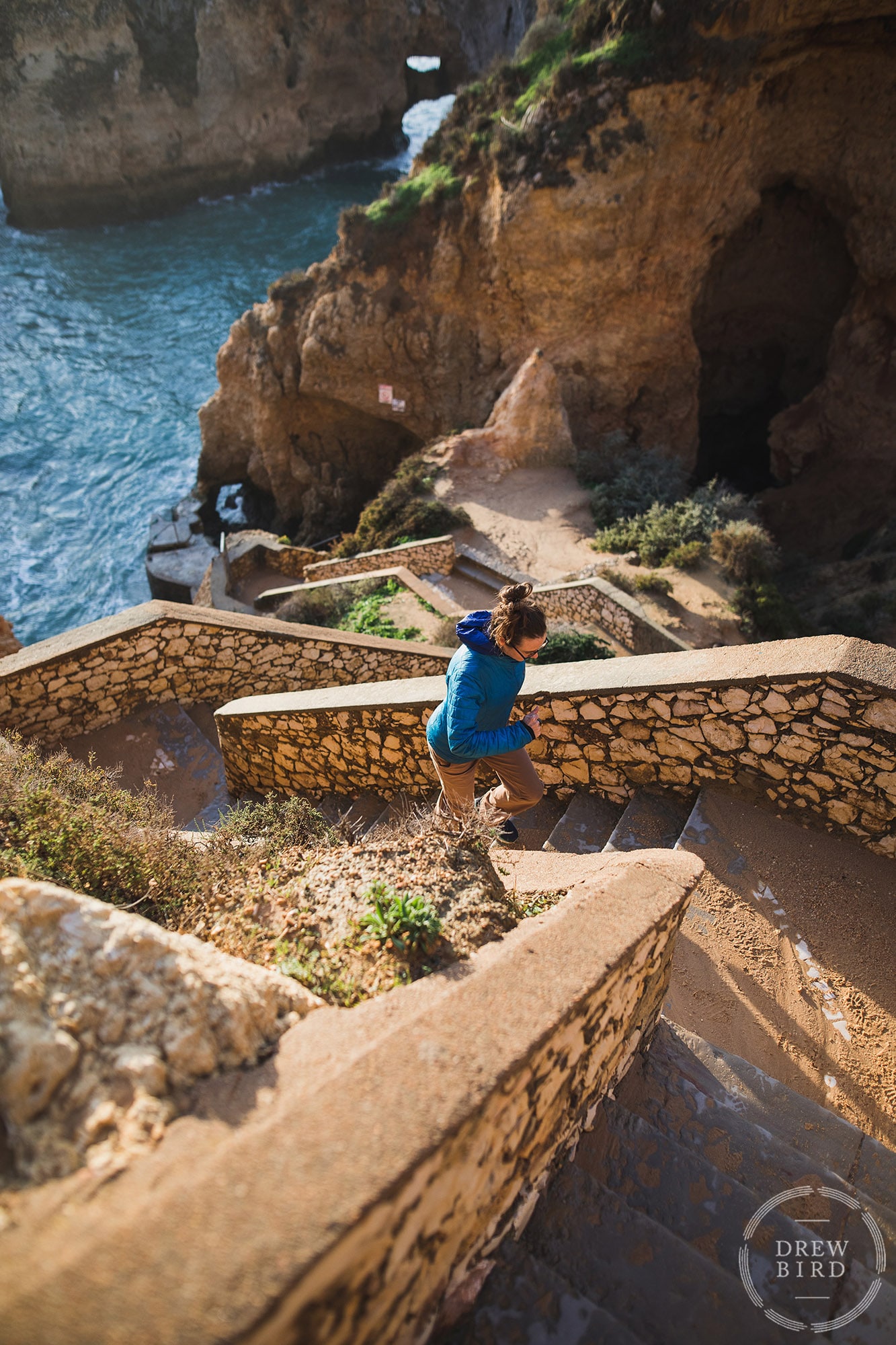 Woman running up stone stairs in Portugal wearing Patagonia jacket. San Francisco brand and commercial photographer Drew Bird.