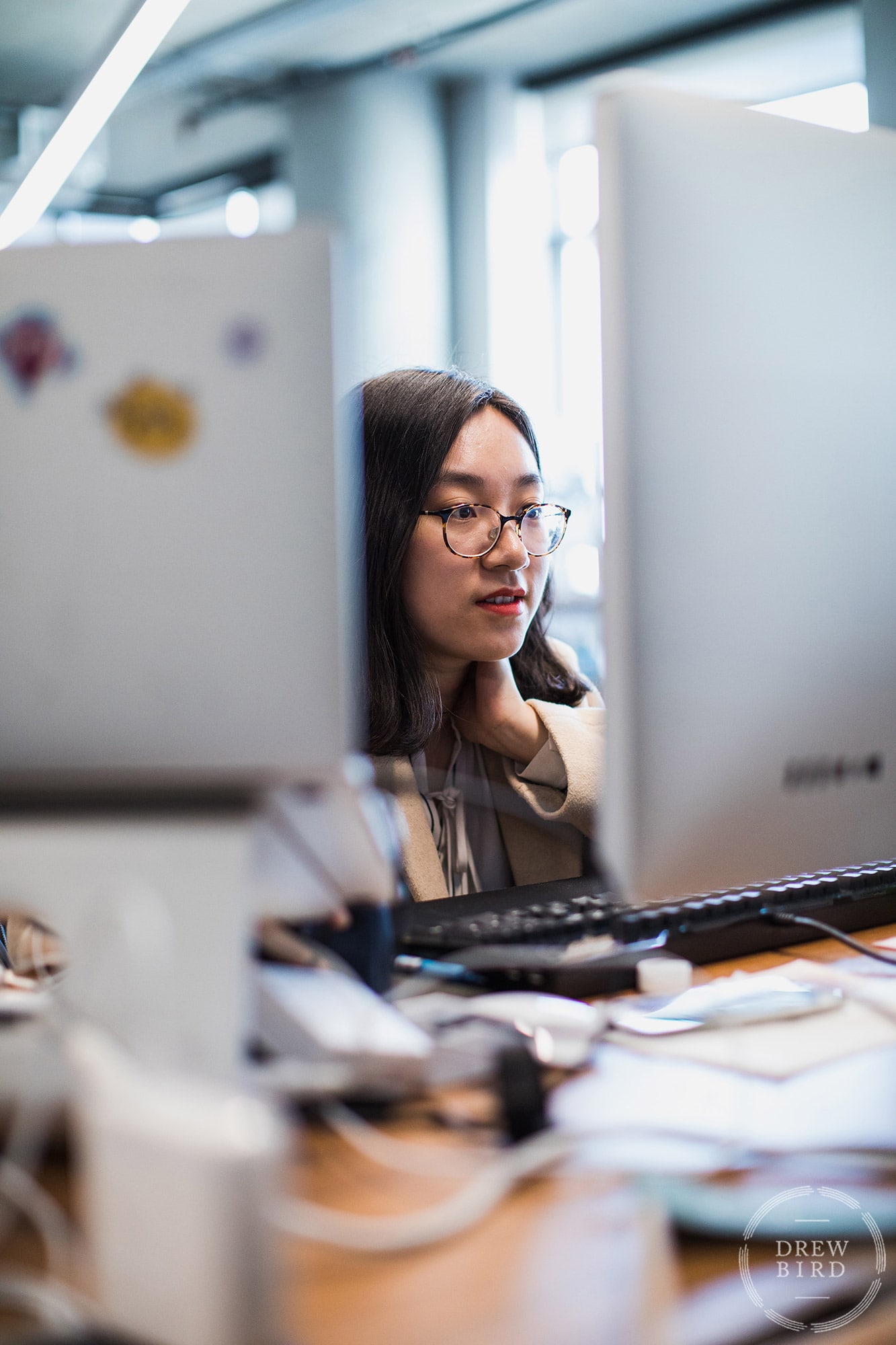 Woman with glasses working at a computer at Dropbox. San Francisco corporate lifestyle photographer Drew Bird.