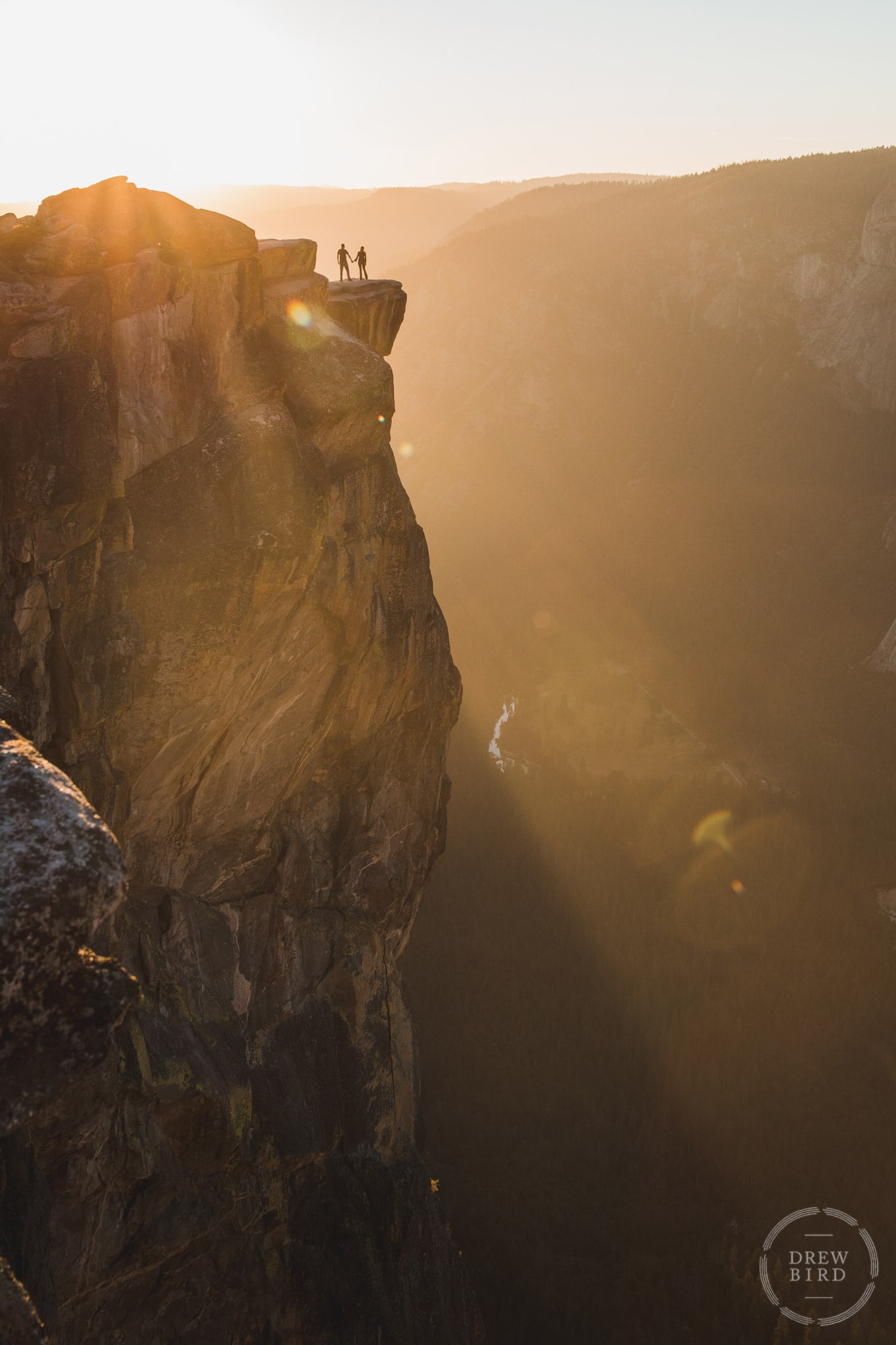 Silhouette of a couple holding hands on Taft Point in Yosemite National Park at Sunset. San Francisco brand and commercial photographer Drew Bird.