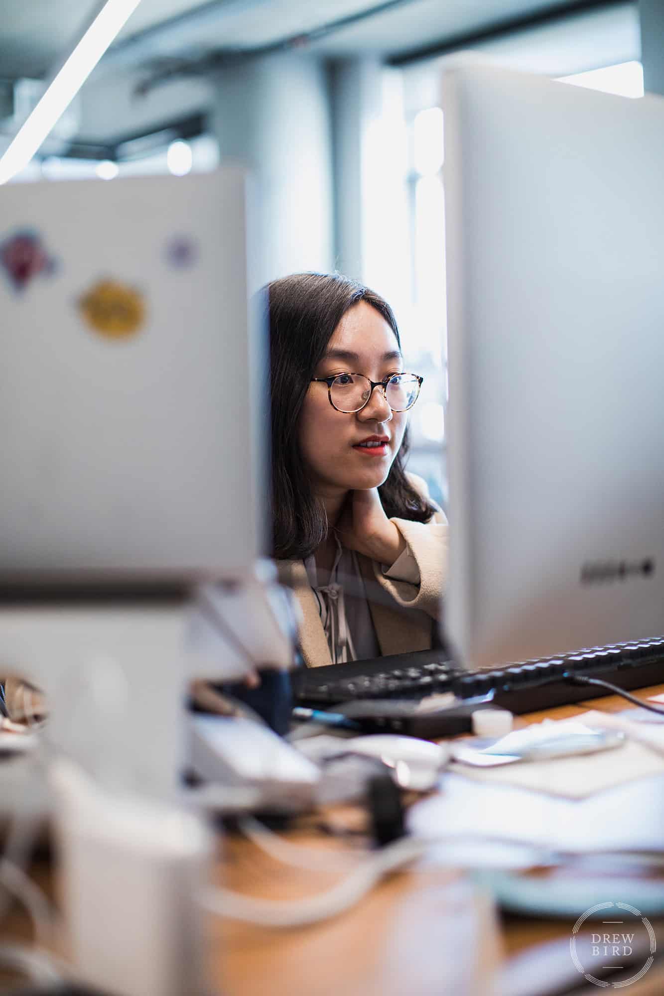 Corporate lifestyle brand photo - woman sitting at desk and working at a computer.