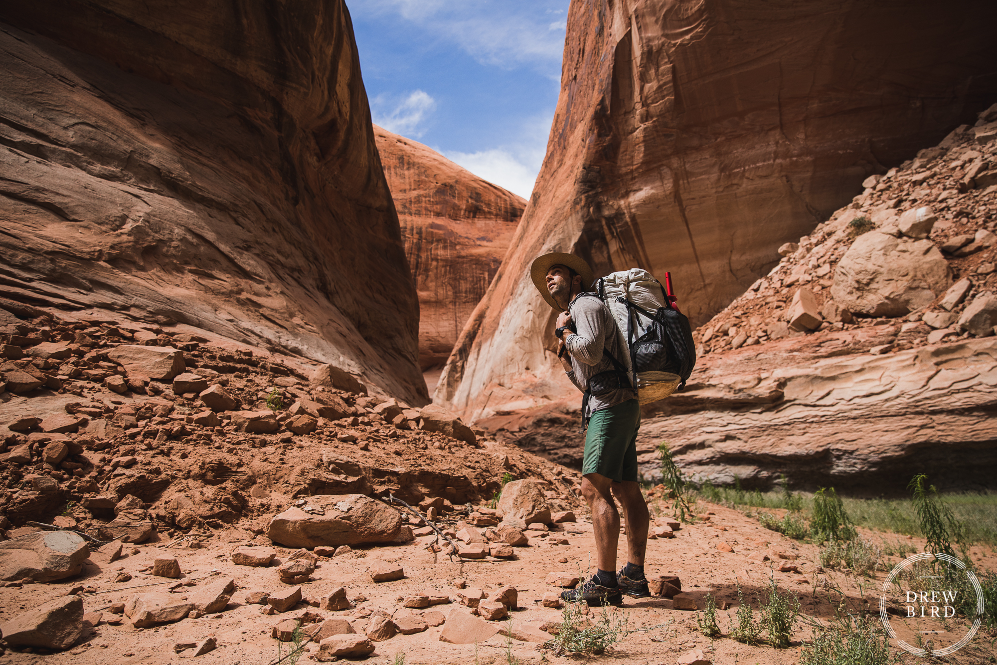 A backpacker stands in a slot canyon in Southern Utah surrounded by redrocks. Adventure photography for Alpaka Packrafts.
